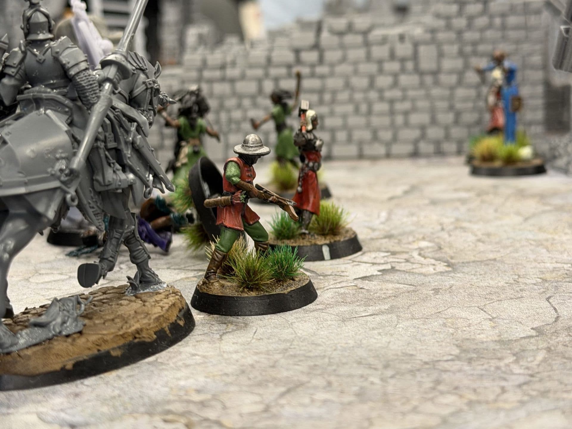 Ruiter en geschilderde miniaturen op grasbases op een stenen straat, met een ruïne op de achtergrond