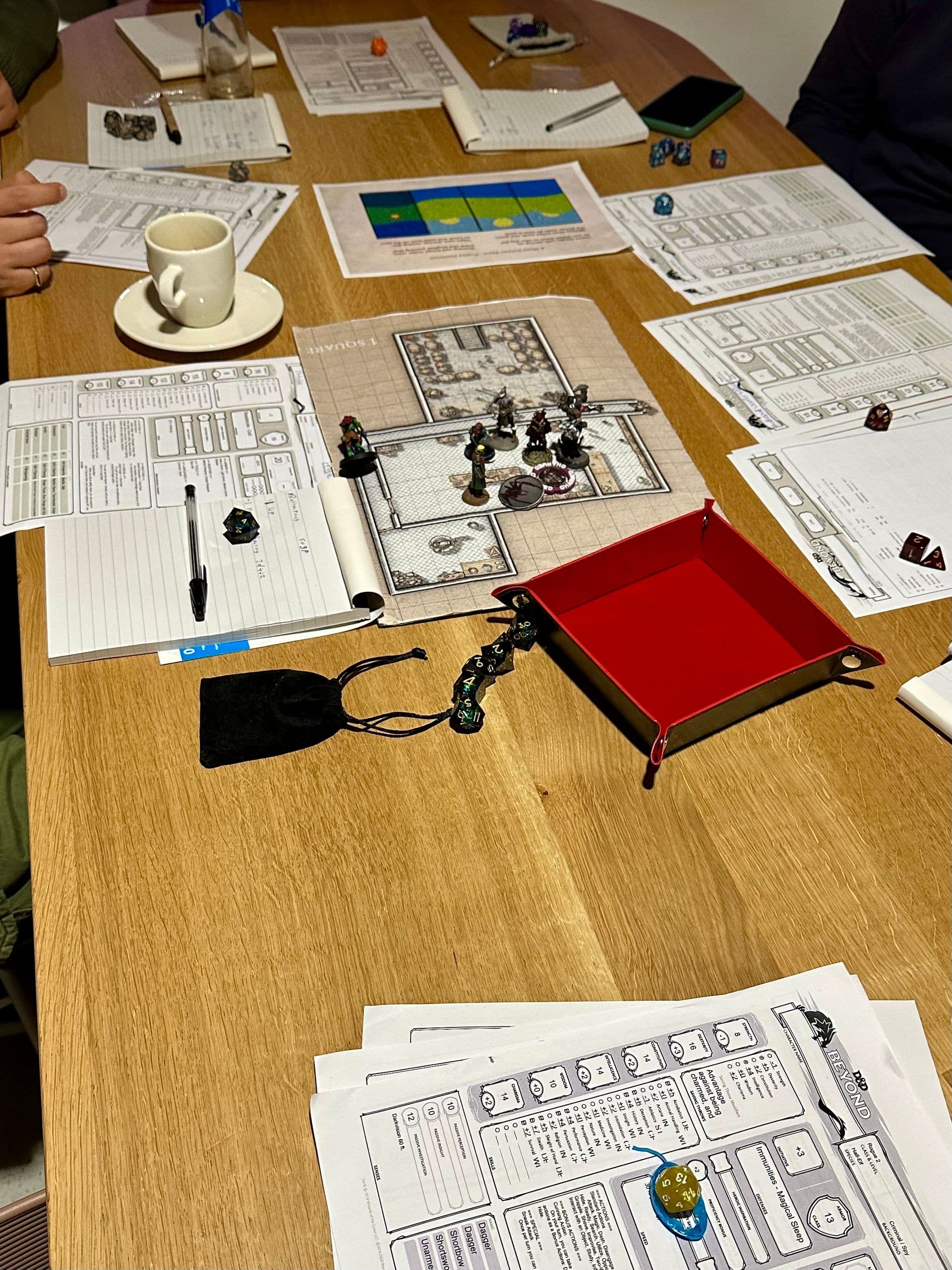 Tafel vol D&D miniaturen op een kaart, met dobbelstenen en character sheets